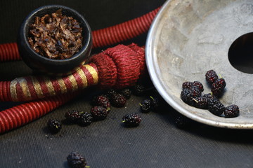 bowl with tobacco for hookah. berries on a black background