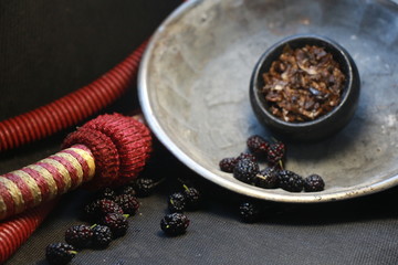 bowl with tobacco for hookah. berries on a black background