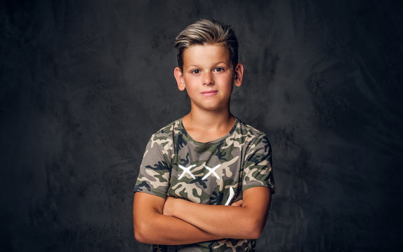 Little charming boy with nice hairstyle is posing over dark background at photo studio.