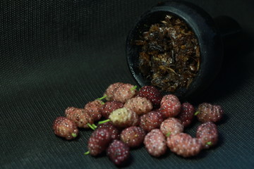 bowl with tobacco for hookah. fruits on a black background. smoke hookah