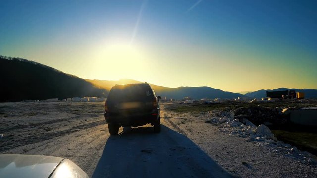 Cinematic following view of jeep suv on offroad rely drive against sunset