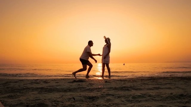 Romantic Silhouette of Man Getting Down on his Knee and Proposing to Woman on Beach- Couple Gets Engaged at Sunset, SLOW MOTION