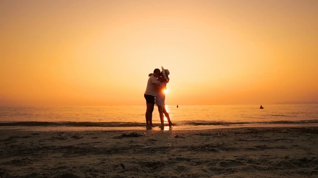 Just married couple kiss and hug on sea beach at sunset, concept of romance, love, happiness, togetherness, SLOW MOTION