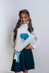 Schoolgirl posing with a bouquet of flowers. Girl in a school suit. Day of Knowledge. September 1.