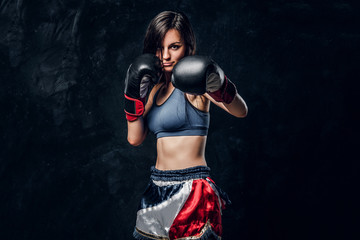 Fototapeta na wymiar Young attractive female boxer with long hair and boxing gloves is ready to fight.