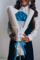 Schoolgirl posing with a bouquet of flowers. Girl in a school suit. Day of Knowledge. September 1.