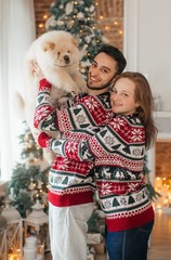 Beautiful new-year portrait of the young falling in love together with the dog of чаучау in Christmas decorations