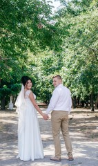 Obraz premium Bride and Groom at wedding Day walking Outdoors on nature. Bridal couple, Happy Newlywed woman and man embracing in green park. Loving wedding couple outdoor. 