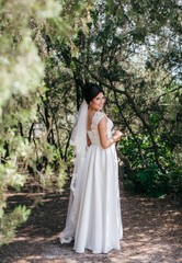 Fototapeta premium Beautiful bride with stylish make-up in white dress in spring garden 