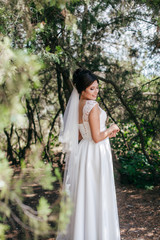 Naklejka premium Beautiful bride with stylish make-up in white dress in spring garden 