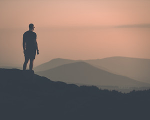 Young confident muscular male stood with a silhouette of mountains in the distance