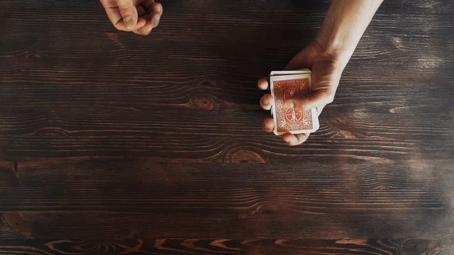 Man showing trick with playing cards. (Hands only). Top down view. Slow motion footage. Only mens hands in frame. Flat lay.