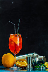 Cocktail aperol spritz in big wine glass with water drops on dark background.