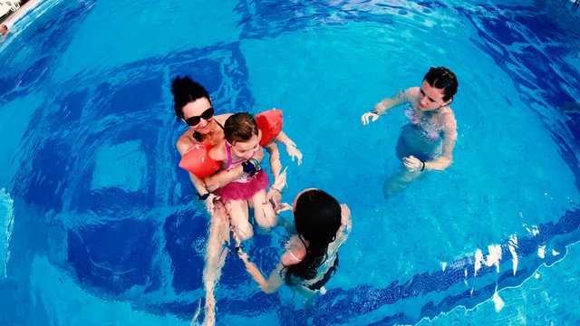 Aerial view of family relaxing in luxury outdoors pool, slow motion