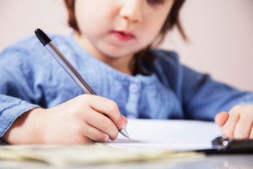 Humorous photo of cute little business child girl signs a contract. Business, agreement, success, profit.