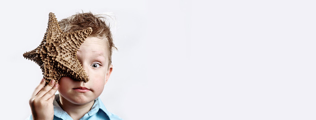 boy in a light t-shirt holding a starfish on a white background