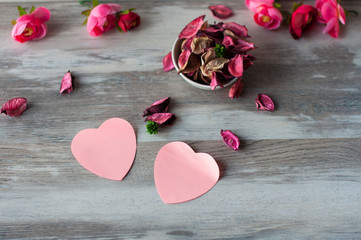 Dry air  petals pink roses lie on the table in a white Cup, near with them lie pink paper hearts