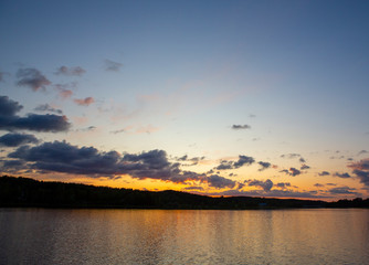 Sunset at the lakeside in Finland during summer evening. Glowing orange horizon.