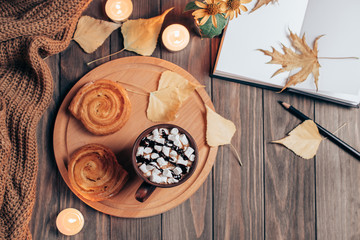 Warm autumn hygge composition with hot chocolate, pastry and notebook on wooden background