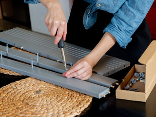 woman with screwdriver instaling a furniture at home personally
