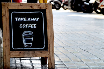 Sidewalk sandwich board sign on the pavement with the message Take Away Coffee