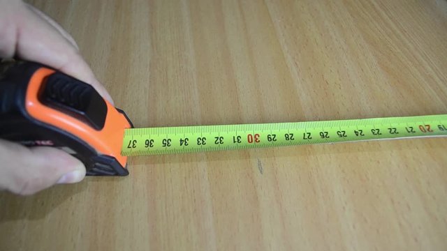 A man measures a desk with a tape and marks