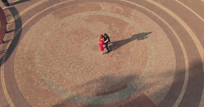 Professional dancers rehearse tango on the street, synchronized steps, body movements. Circular motion of the camera. View from copter. Top view.