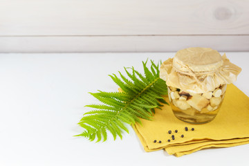 Pickled mushrooms in a jar on a light background. Fermented food, horizontal orientation.