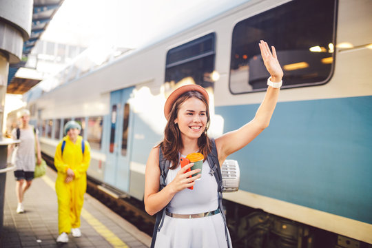 backpack traveler woman waving hand at train station platform summer holiday traveling concept. Female tourist greeting and enjoy on train, travel concept. Theme transportation and travel