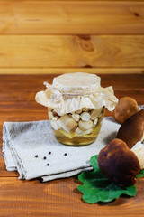 Marinated mushrooms in a jar on a wooden table. Fermented food.