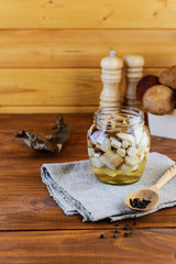 Marinated mushrooms in a jar on a wooden table. Fermented food.