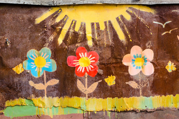 Drawing flowers and the sun on the wall. The wall is made of iron, and the picture is painted with bright colors.