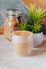 glass of latte coffee on light table with almond nuts