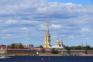 Russia, Petersburg, June 29, 2019. Spit of Vasilyevsky Island. The photo shows the Peter and Paul Fortress on the bank of the Neva against the sky and a pleasure boat