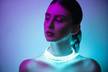 High Fashion woman in colorful bright neon uv blue and purple lights, posing in studio, beautiful girl, glowing make-up, colorful make up.