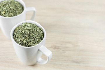 white cup with moringa leaves on wooden background