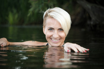 Close-up of a woman blonde middle-aged swims in the river, selective focus