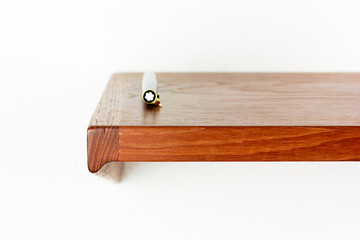 midcentury teak shelf on white wall in the living room with a wooden vase and a plack pen on it next to it a space age vintage orange lamp danish design front side low angle high view HIGH RESOLUTION