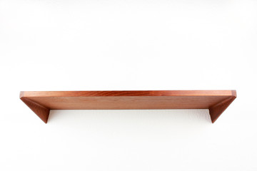 midcentury teak shelf on white wall in the living room with a wooden vase and a plack pen on it next to it a space age vintage orange lamp danish design front side low angle high view HIGH RESOLUTION