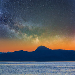 sea bay with rocky coast silhouette under a starry sky, twilight scene