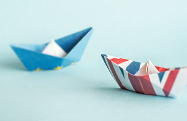 rust crack paper ships from the flags of the European Union and the UK on a blue background, concept of Brexit