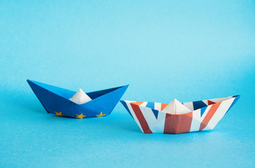 rust crack paper ships from the flags of the European Union and the UK on a blue background, concept of Brexit