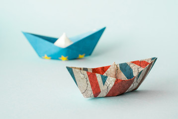 rust crack paper ships from the flags of the European Union and the UK on a blue background, concept of Brexit