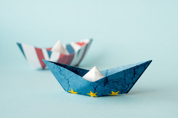 rust crack paper ships from the flags of the European Union and the UK on a blue background, concept of Brexit