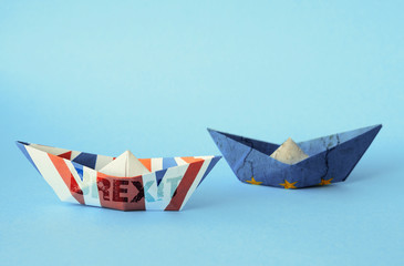 rust crack paper ships from the flags of the European Union and the UK on a blue background, concept of Brexit