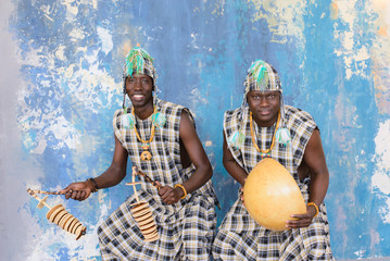 African artists with traditional musical instruments on blue wall background.