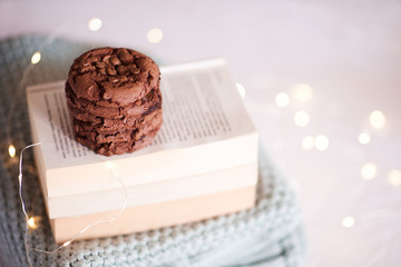 Chocolate cookies on books over Christmas lights closeup. Winter season. Good morning. Homemade tasty pastry. New Year.