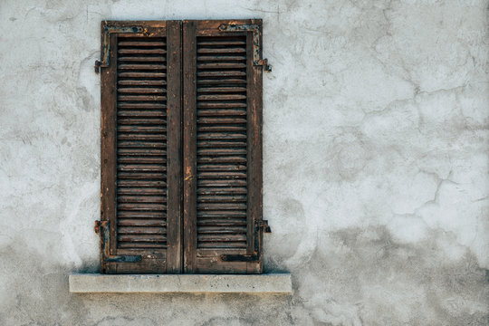 old window with wooden shutters with cracked wall