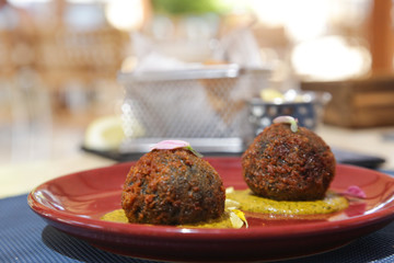 Squid ink Arancini, breadcrumb coated rice balls with squid ink served on the ceramic red plate