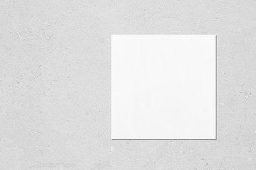 Empty white square flyer or business card mockup with soft shadows on neutral light grey concrete...